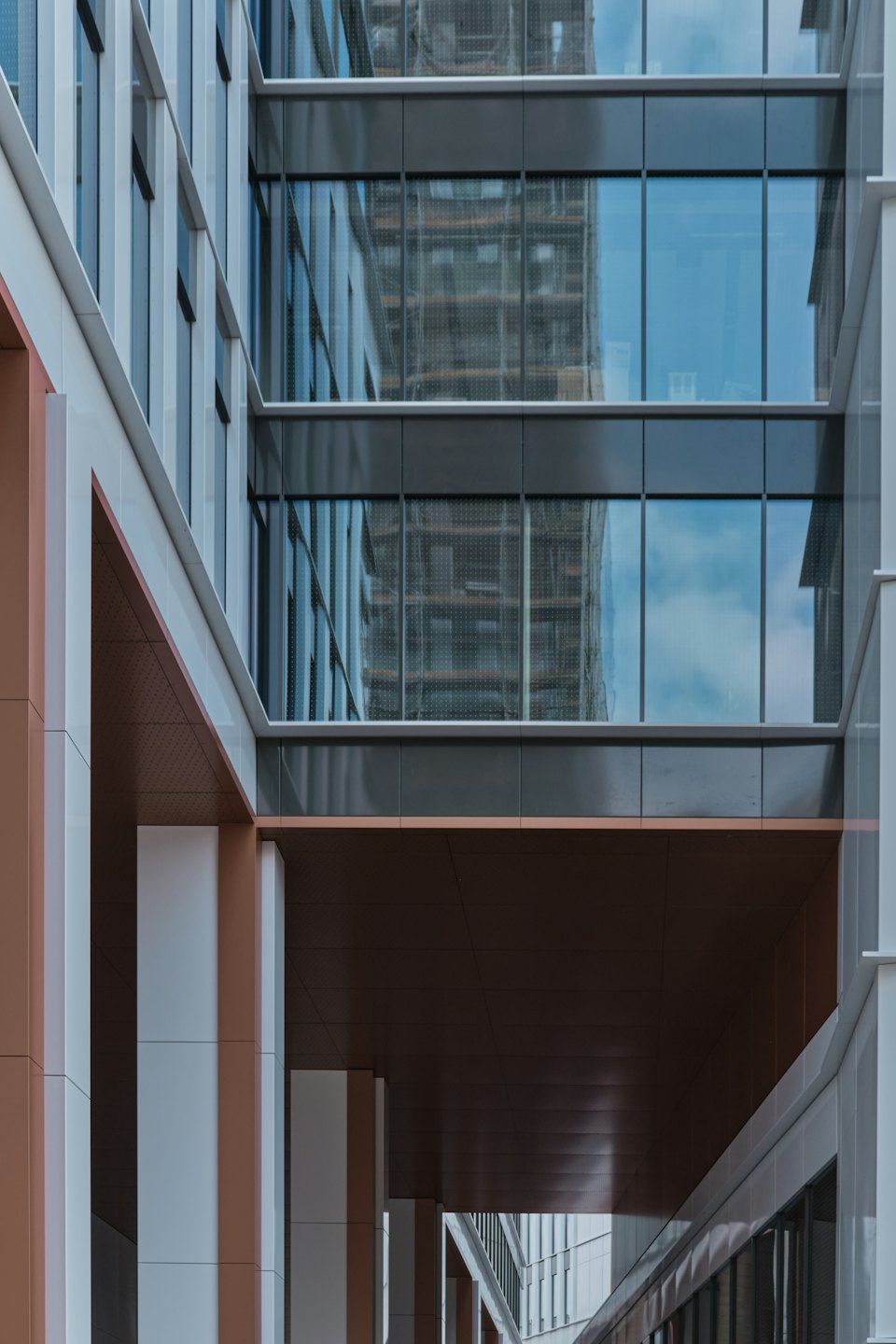 Facciata di un edificio moderno con motivi geometrici e finestre in vetro che riflettono il cielo.